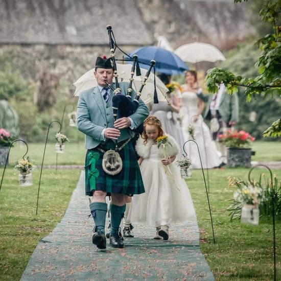 Wedding Piper leading the Bridal Party to the ceremony. Outside Scottish Castle Wedding at Tullibole Castle